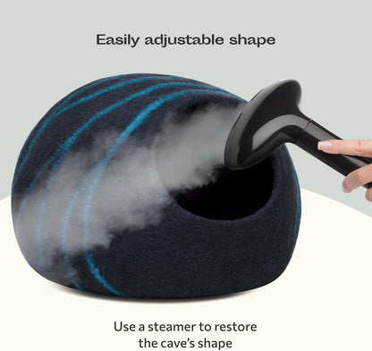 Black and aquat marbled cat bed being steamed with a hand holding a steamer, on a light gray background.
