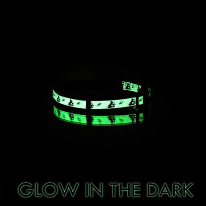 Glowing green cat collar with black patterns on a black background